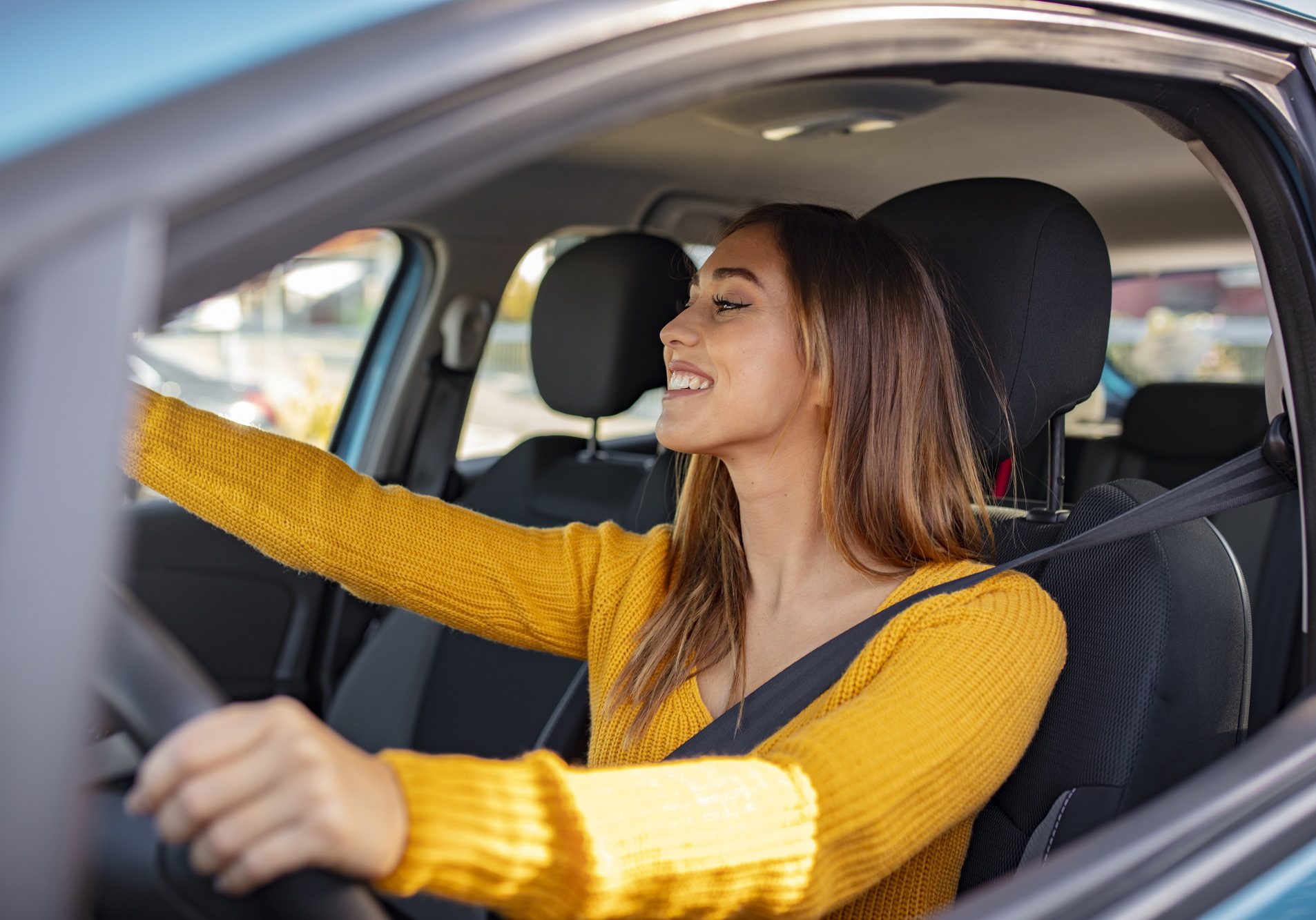 Beautiful female Driver adjusting the Rear Mirror looking at herself. Adjusting the rear view mirror. Woman adjusts the rear view mirror with her hand. Happy young woman driver looking adjusting rear view car mirror